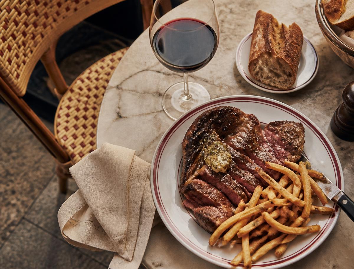 Steak frites and a glass of red wine on a marble bistro table